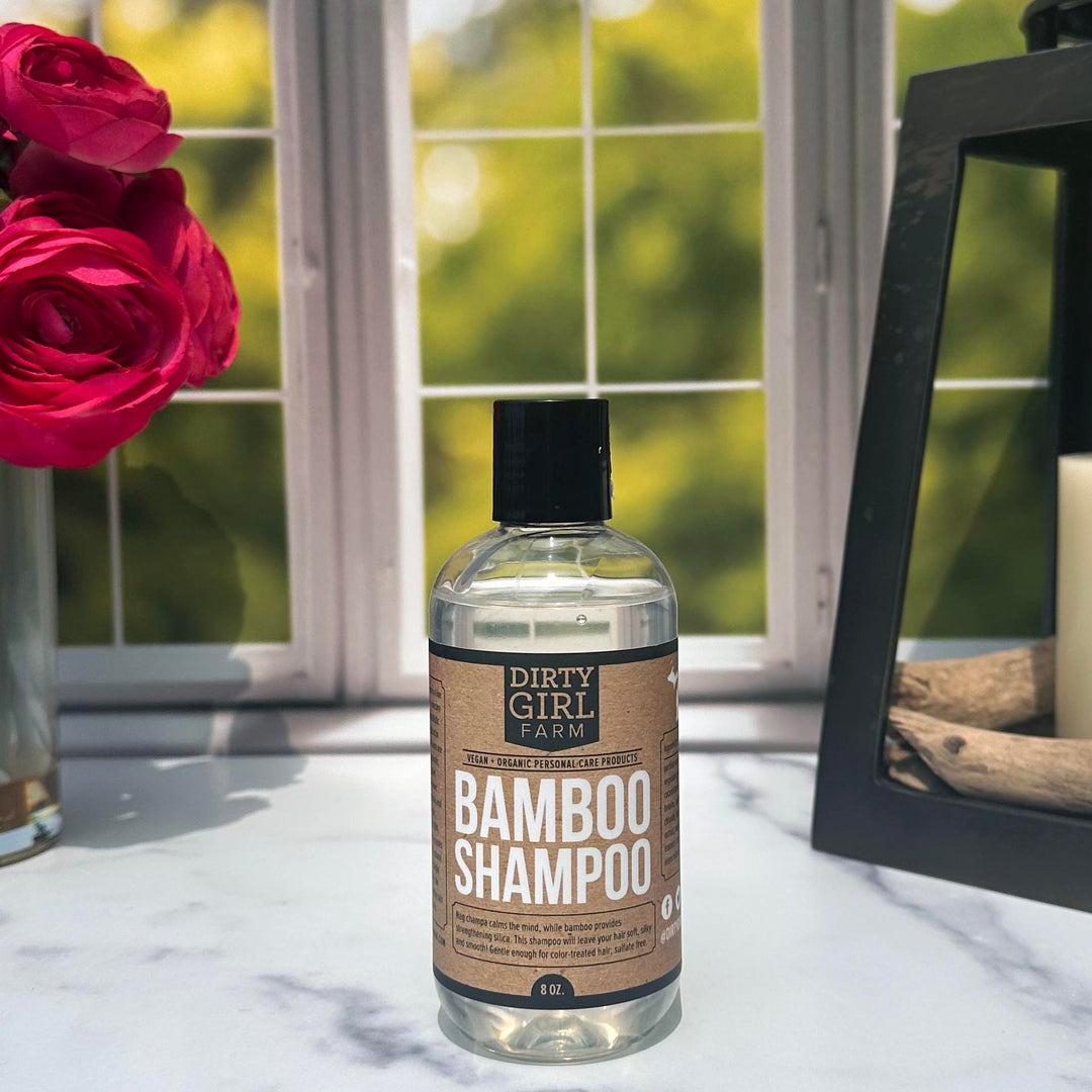 Dirty Girl Farm Bamboo Shampoo on a counter with a vase and candle.